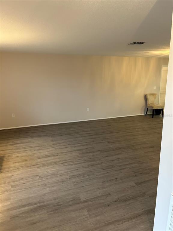 A spacious, empty room features light-colored walls, wood-look flooring, and a single chair — 209 MATISSE CIRCLE, NOKOMIS, FL
