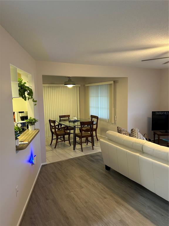 A living room with light flooring leads to a dining area with a glass table — 209 MATISSE CIRCLE, NOKOMIS, FL