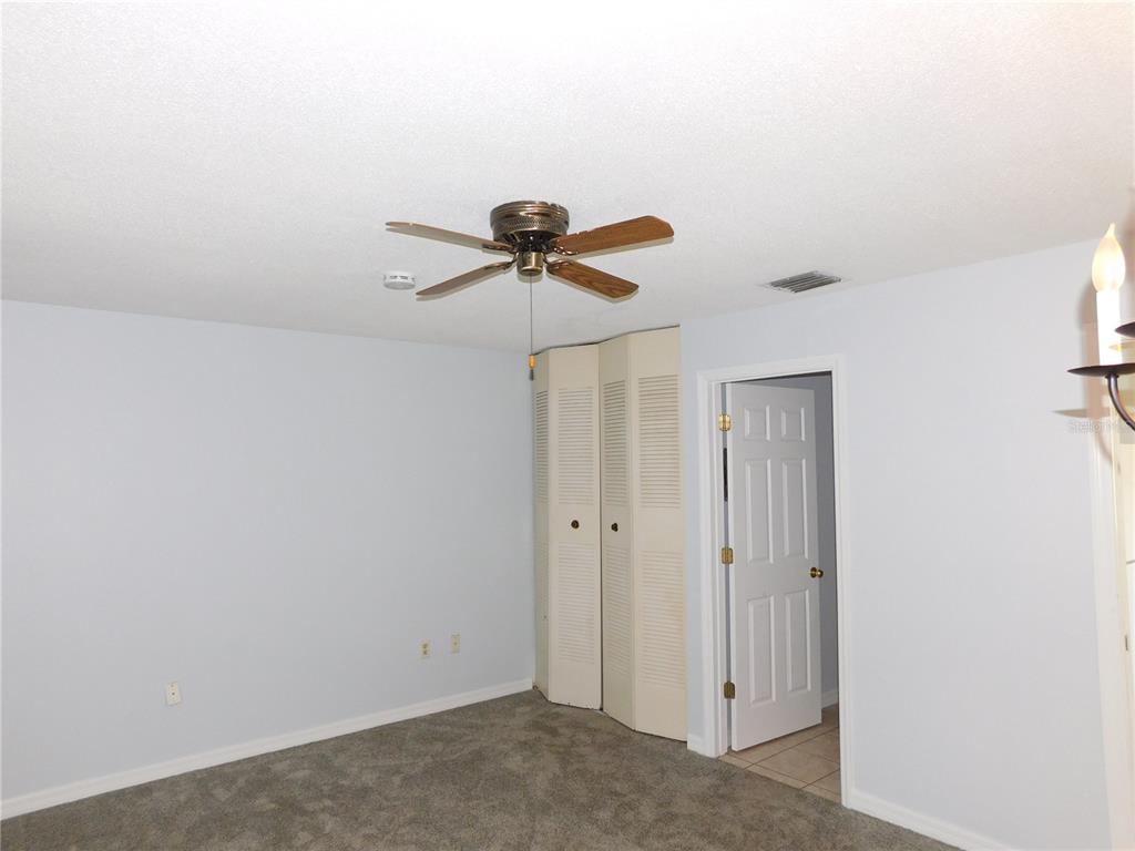 A bedroom with gray carpet, light blue walls, a ceiling fan, and a closet — 1118 SPRING MEADOW DRIVE, KISSIMMEE, FL