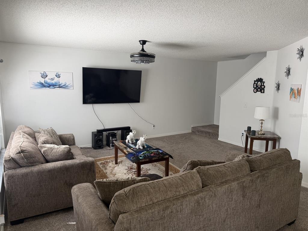 A living room features two gray sofas, a wall-mounted television, and a coffee table — 7135 WATERSIDE DRIVE, TAMPA, FL