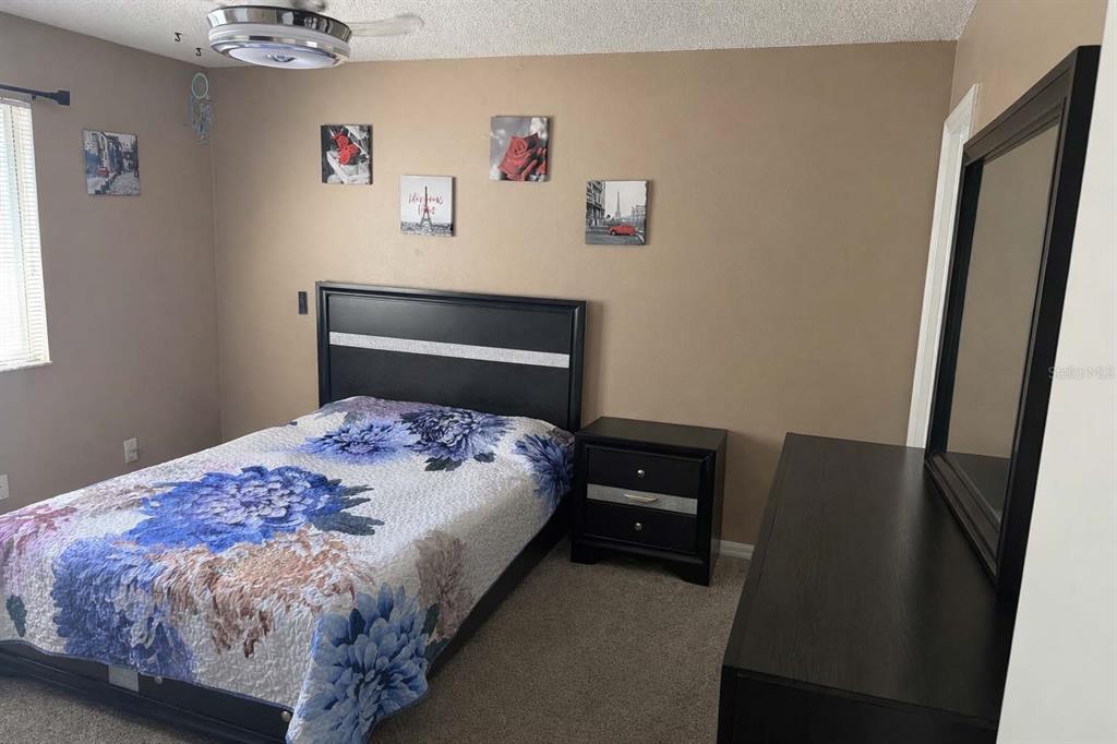 A bedroom features a black bed frame, a matching nightstand, and a dresser with mirror — 7135 WATERSIDE DRIVE, TAMPA, FL