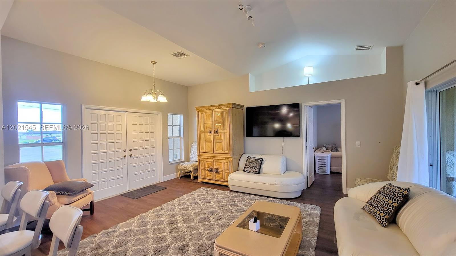 A living room features a vaulted ceiling, white double doors, and a large area rug — 7018 PILGRIM CT, La Belle FL 33935, LA BELLE, FL