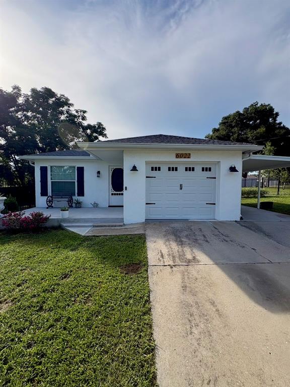 A white single-story house with a garage, a front porch, and a concrete driveway — 6022 POLK AVENUE NW, LAKELAND, FL