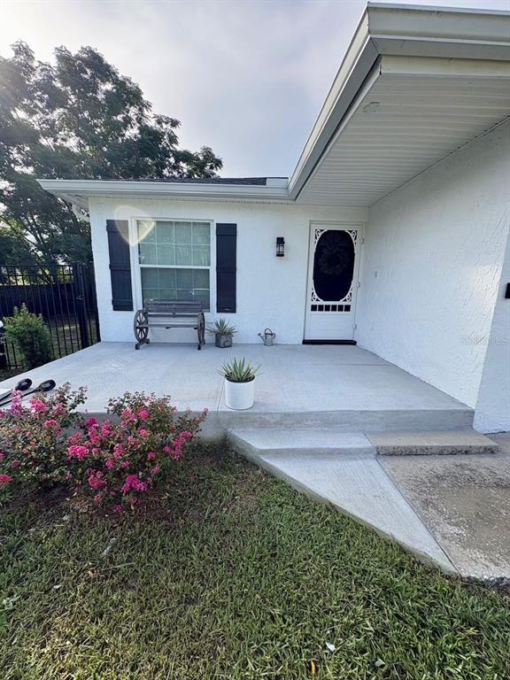 A white house exterior features a concrete porch, a front door with a screen, and shutters — 6022 POLK AVENUE NW, LAKELAND, FL