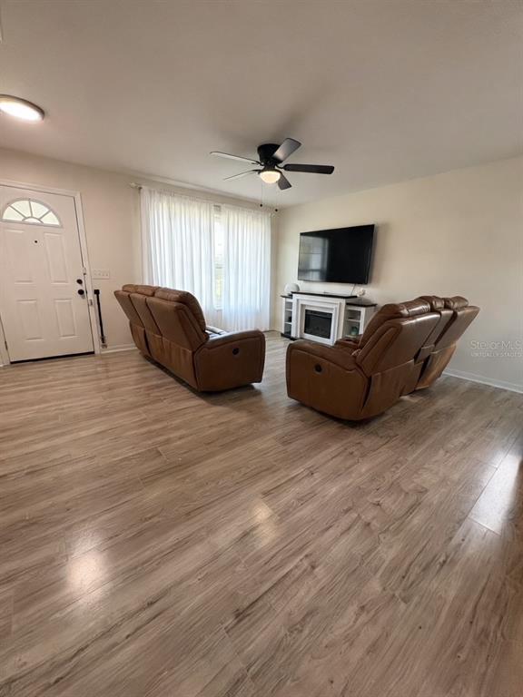 A living room features light wood-look flooring, two brown reclining sofas, and a wall-mounted television — 6022 POLK AVENUE NW, LAKELAND, FL