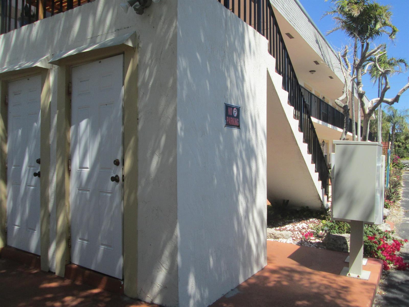 Exterior view of a white building with two doors, a staircase, and a parking sign — 405 N Cypress Drive # 8, Jupiter FL 33469, JUPITER, FL