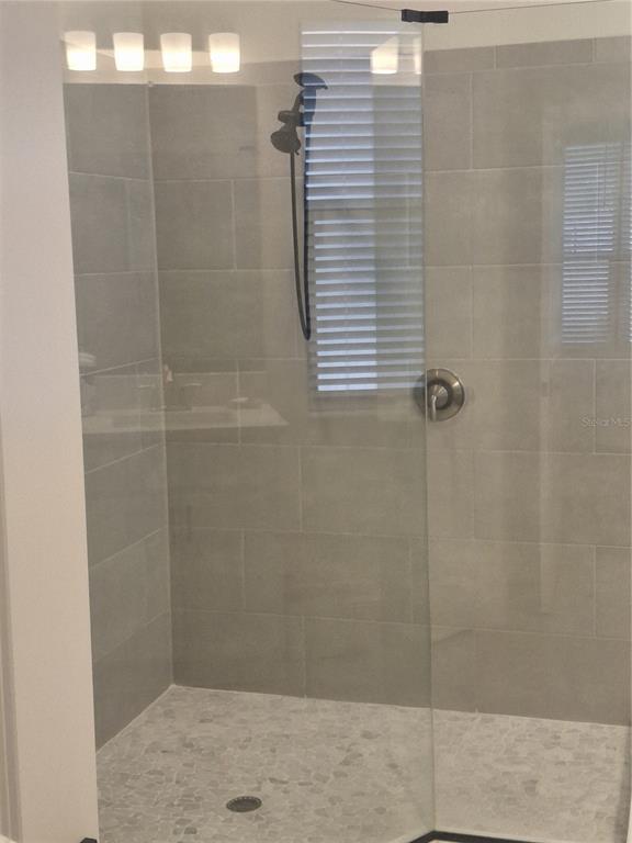 A walk-in shower features gray subway tile walls, a pebble floor, and a glass door — 12618 VANDER WAY, NEW PORT RICHEY, FL