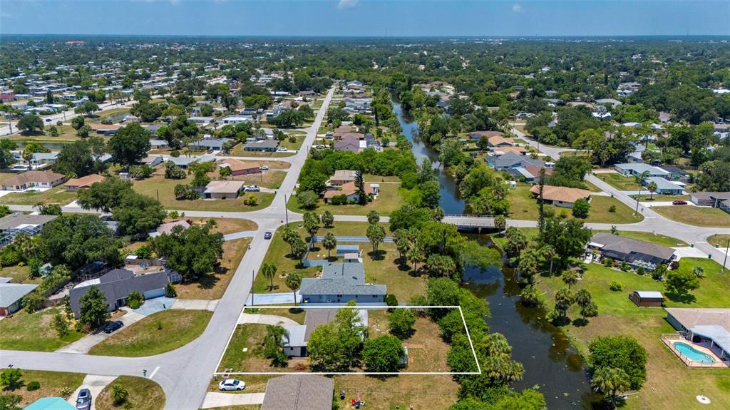 An aerial view shows a single-story house with a large yard bordering a canal — 21358 BURKHART DRIVE, PORT CHARLOTTE, FL