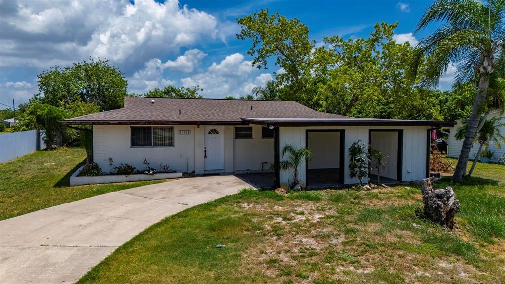 A single-story house with a white exterior, a brown roof, and an attached carport — 21358 BURKHART DRIVE, PORT CHARLOTTE, FL