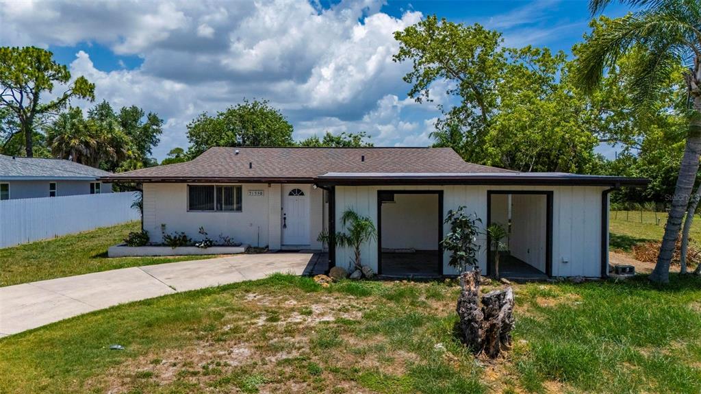 A single-story house with a white exterior, a brown roof, and an attached carport — 21358 BURKHART DRIVE, PORT CHARLOTTE, FL