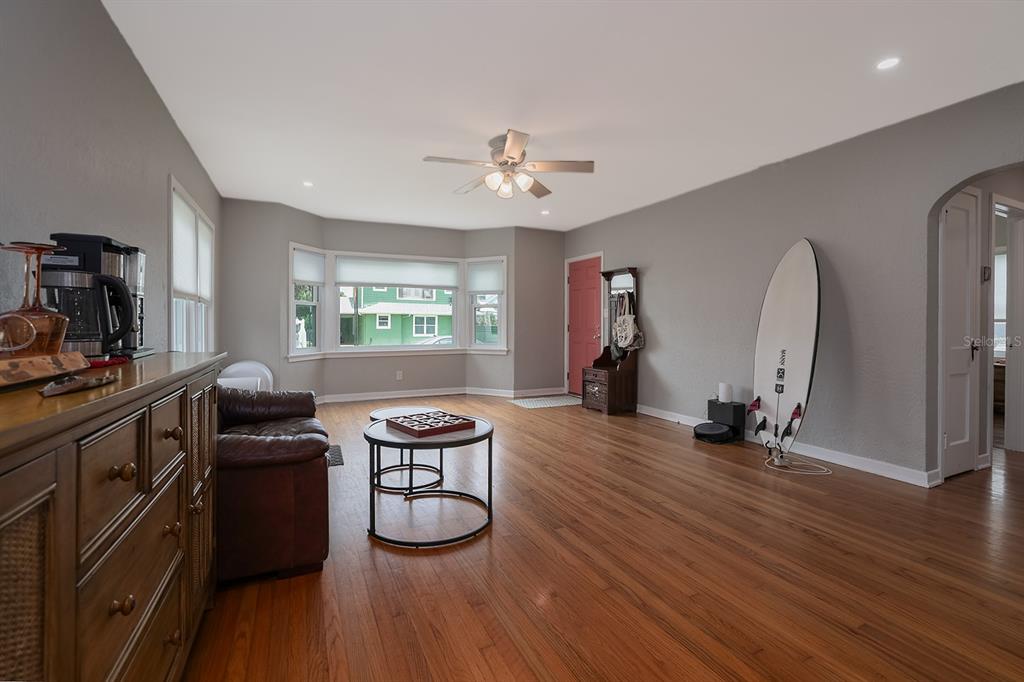 A living room features hardwood floors, a bay window, a ceiling fan, and a surfboard — 532 HILLSIDE AVENUE, DAYTONA BEACH, FL
