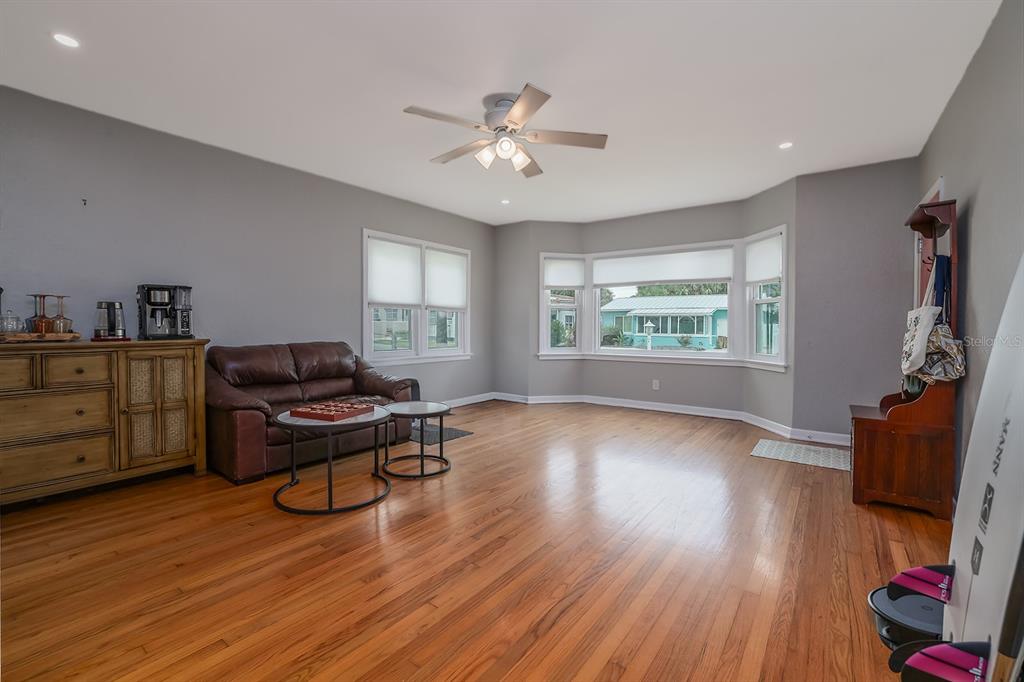 A living room features hardwood floors, gray walls, a brown leather sofa, and a bay window — 532 HILLSIDE AVENUE, DAYTONA BEACH, FL
