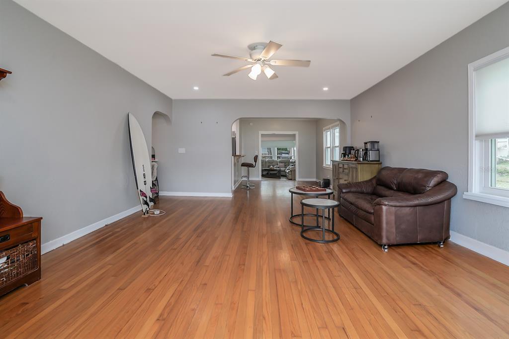 A living room with hardwood floors, a brown leather sofa, and a surfboard leaning against the wall — 532 HILLSIDE AVENUE, DAYTONA BEACH, FL
