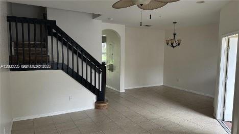 An interior view shows a tiled living area with a staircase featuring black railings — 2851 W Prospect Rd # 1211, Tamarac FL 33309, TAMARAC, FL