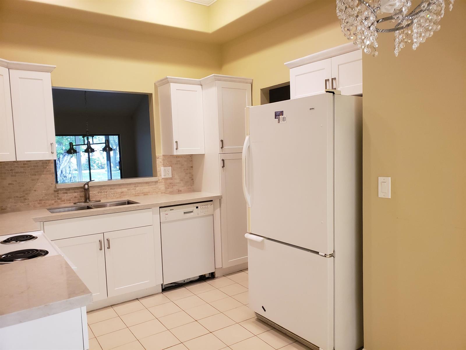 A kitchen features white cabinets, a white refrigerator, a dishwasher, and a tile floor — 10875 Lake Front Place, Boca Raton FL 33498, BOCA RATON, FL