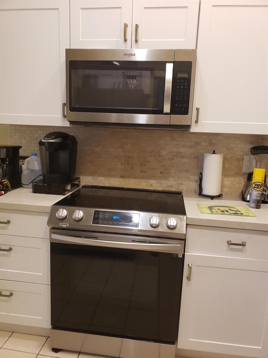 A kitchen features white cabinets, a stainless steel microwave, and a glass-top electric range — 10875 Lake Front Place, Boca Raton FL 33498, BOCA RATON, FL
