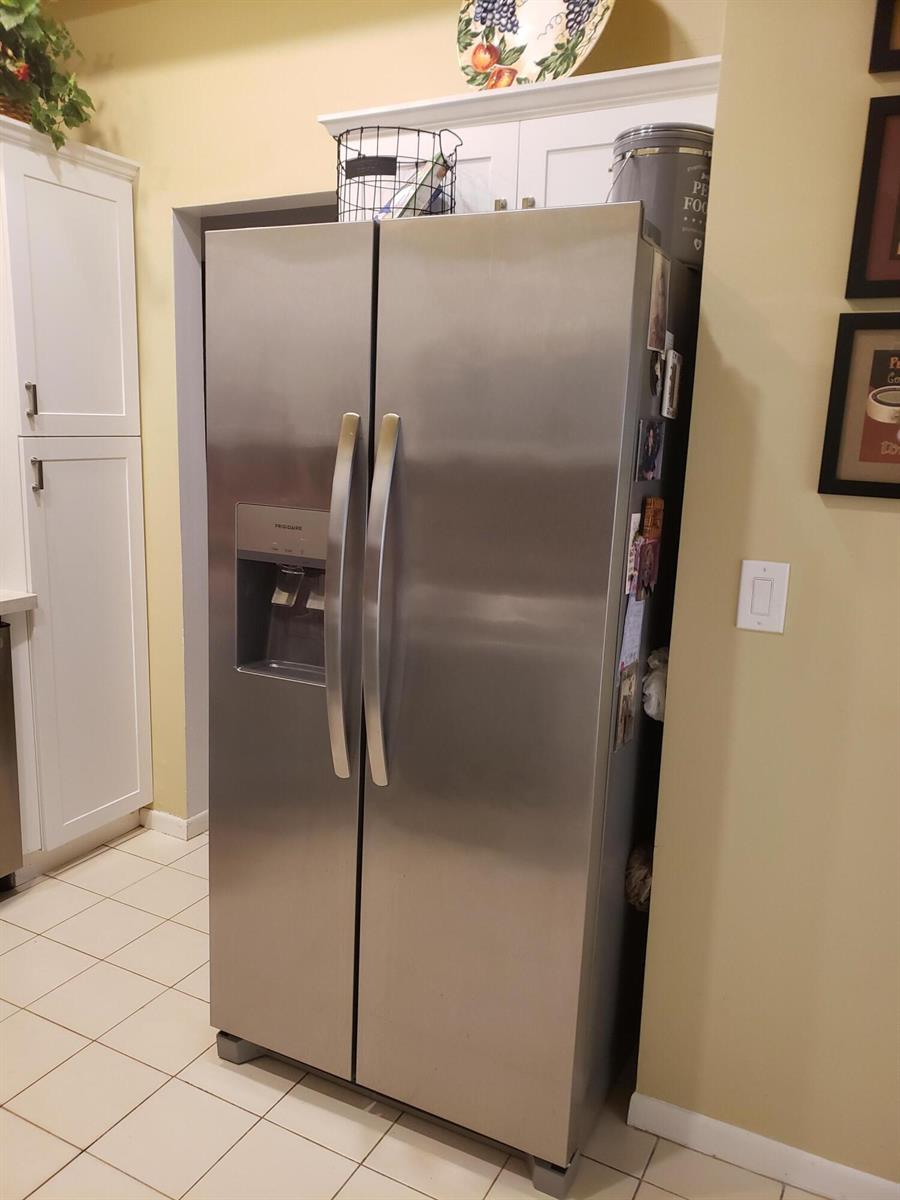 A stainless steel side-by-side refrigerator stands in a kitchen next to white cabinets — 10875 Lake Front Place, Boca Raton FL 33498, BOCA RATON, FL