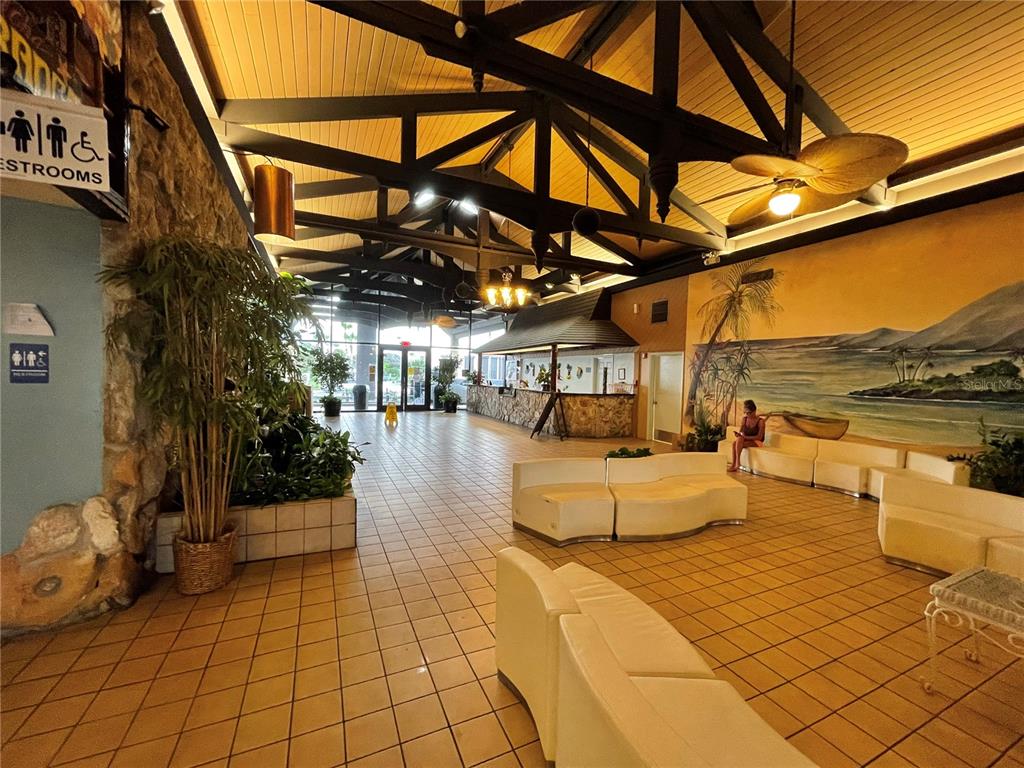 A hotel lobby features tiled floors, white curved seating, a stone wall, and vaulted ceilings — 2301 S ATLANTIC AVENUE UNIT 328, DAYTONA BEACH SHORES, FL