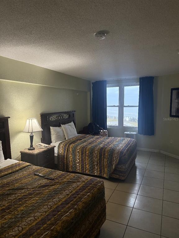 A bedroom with two beds, a nightstand with a lamp, and a window overlooking the ocean — 2301 S ATLANTIC AVENUE UNIT 328, DAYTONA BEACH SHORES, FL