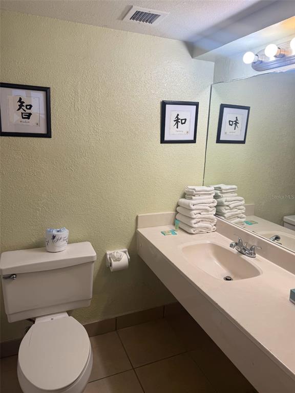 A bathroom features a toilet, a vanity with a sink, and framed wall art — 2301 S ATLANTIC AVENUE UNIT 328, DAYTONA BEACH SHORES, FL