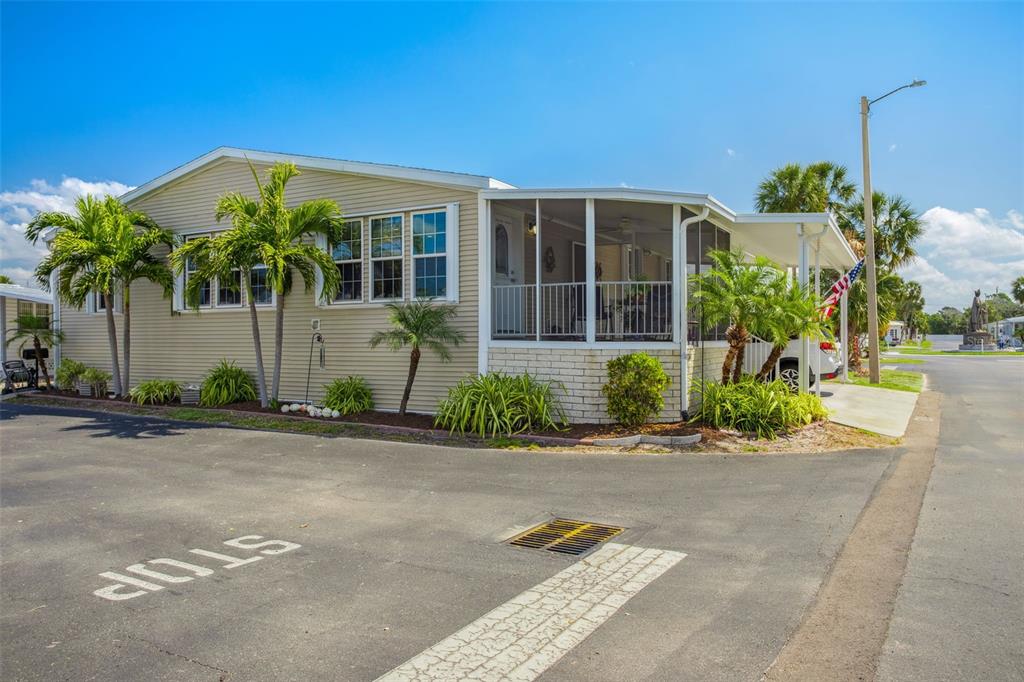 A single-story manufactured home with a screened-in porch, palm trees, and a paved driveway — 4851 W GANDY BOULEVARD UNIT B09L23, TAMPA, FL
