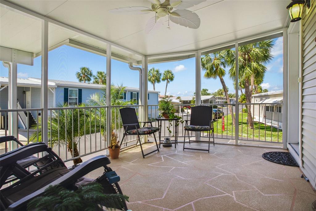 A screened-in porch features a patterned concrete floor, a ceiling fan, and outdoor furniture — 4851 W GANDY BOULEVARD UNIT B09L23, TAMPA, FL