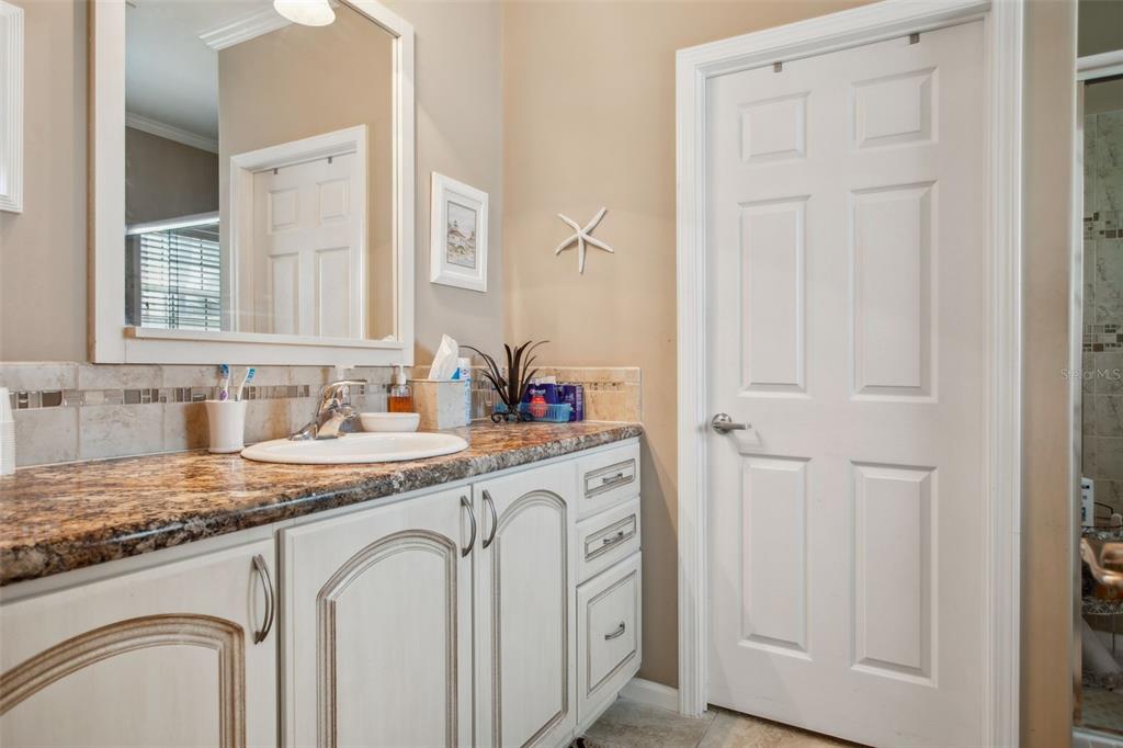 A bathroom vanity with a granite countertop, white cabinets, and a framed mirror — 4851 W GANDY BOULEVARD UNIT B09L23, TAMPA, FL