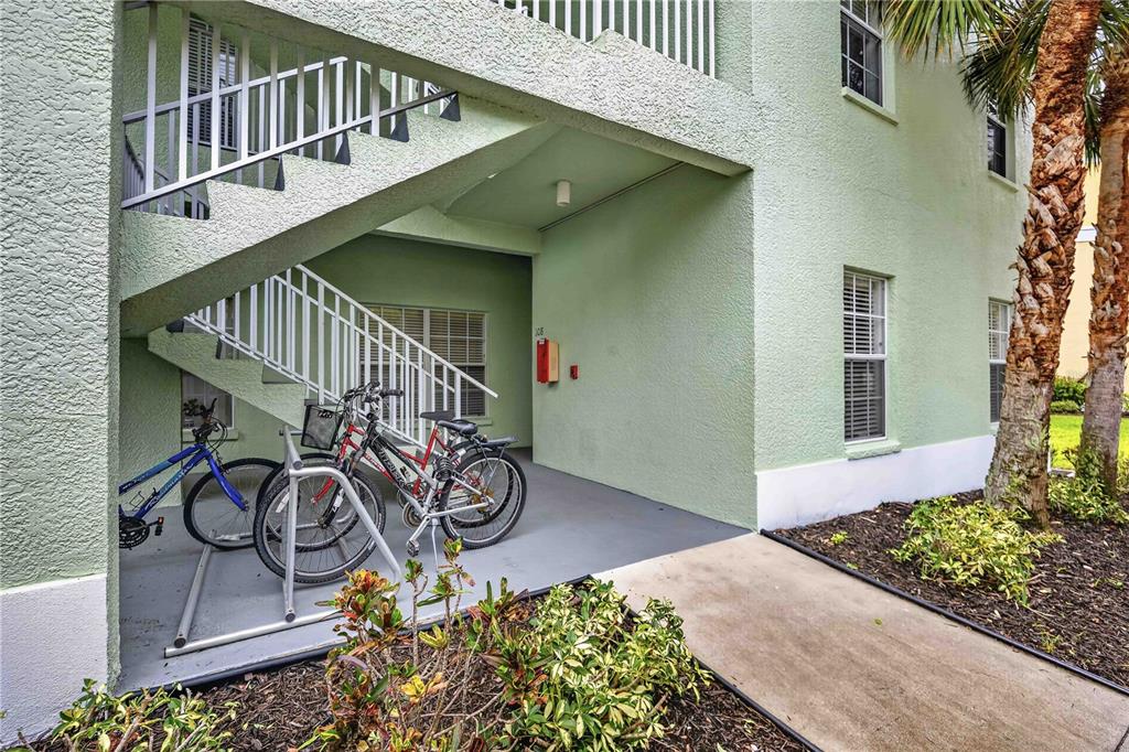 The exterior of a light green apartment building features a staircase and a bicycle rack — 2160 HERON LAKE DRIVE UNIT 108, PUNTA GORDA, FL