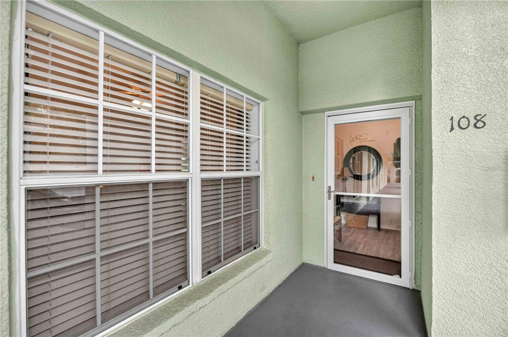 A light green exterior entryway features a white-framed glass storm door and a large window — 2160 HERON LAKE DRIVE UNIT 108, PUNTA GORDA, FL