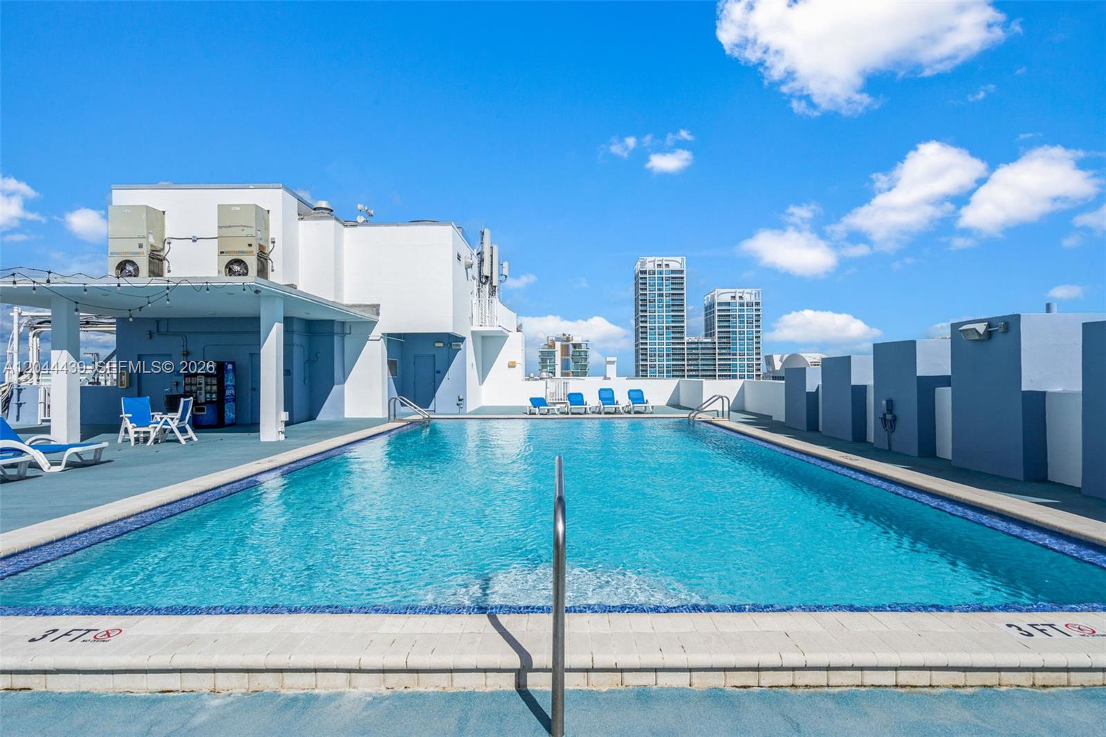 A rooftop swimming pool with lounge chairs and city buildings in the background — 401 69th St # 1012, Miami Beach FL 33141, MIAMI BEACH, FL