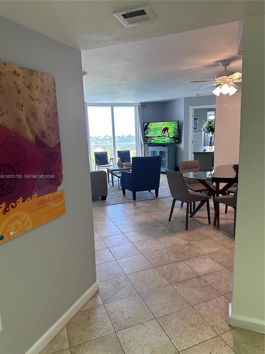 A tiled entryway leads into an open-concept living and dining area with a balcony view — 5880 W Collins Ave # 1203, Miami Beach FL 33140, MIAMI BEACH, FL