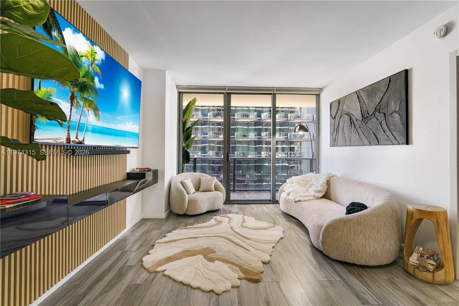 A modern living room features a slatted wood accent wall, a curved sofa, and balcony views — 801 S Miami Ave # 3107, Miami FL 33130, MIAMI, FL