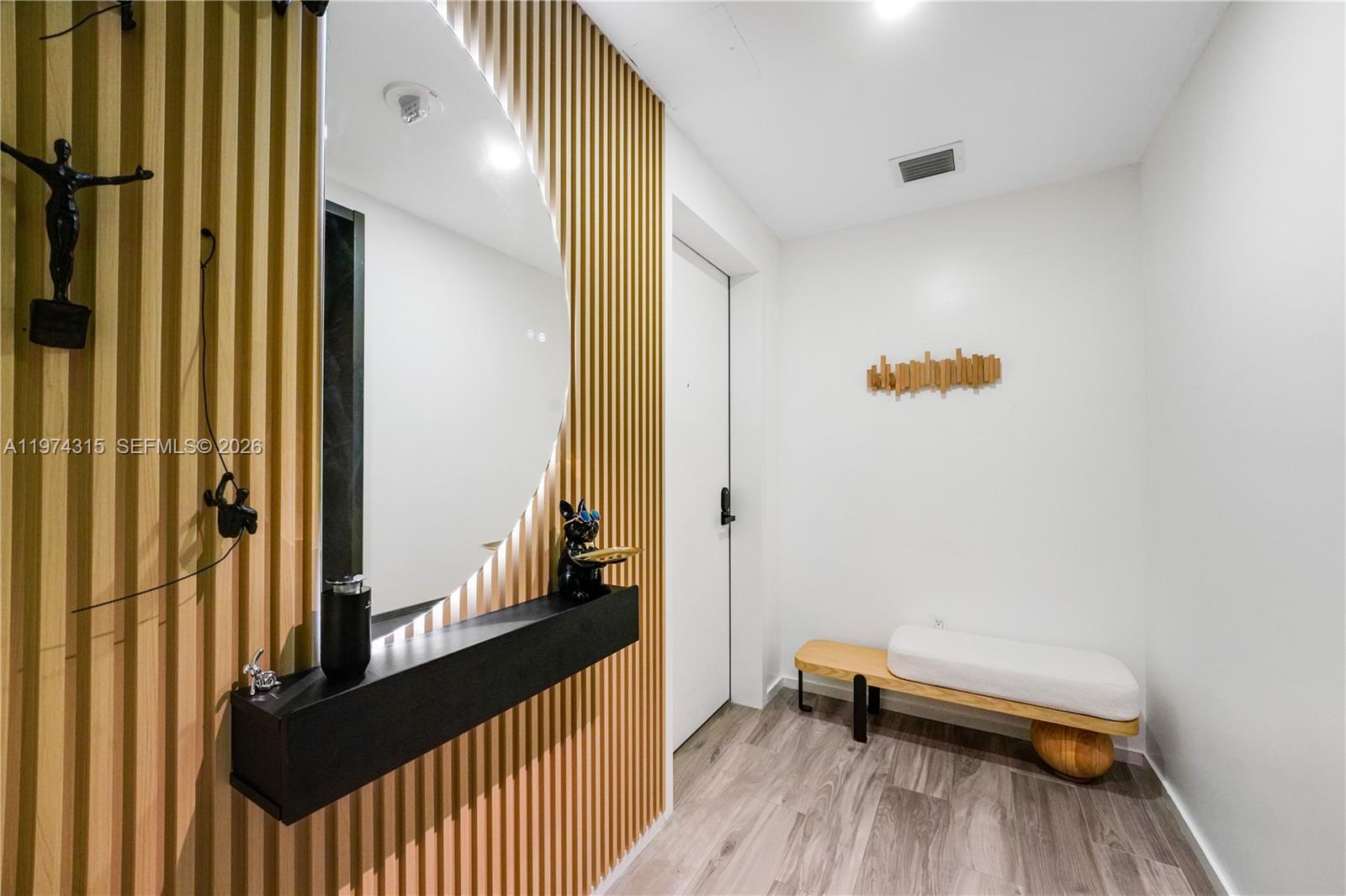 An entryway features a slatted wood wall, a round mirror, a floating shelf, and a bench — 801 S Miami Ave # 3107, Miami FL 33130, MIAMI, FL