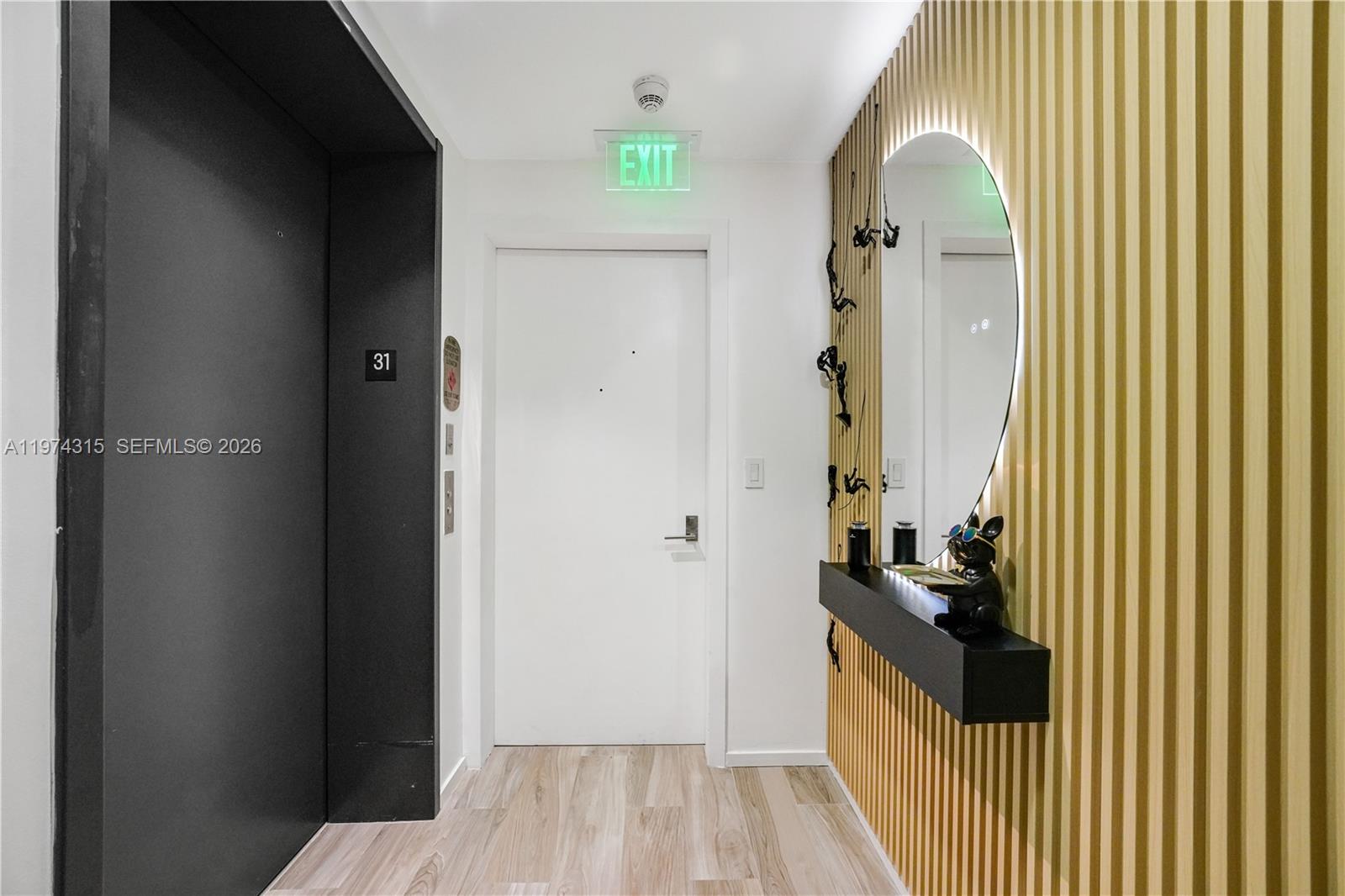 A hallway features a white door, a black elevator entrance, and a slatted wood wall — 801 S Miami Ave # 3107, Miami FL 33130, MIAMI, FL