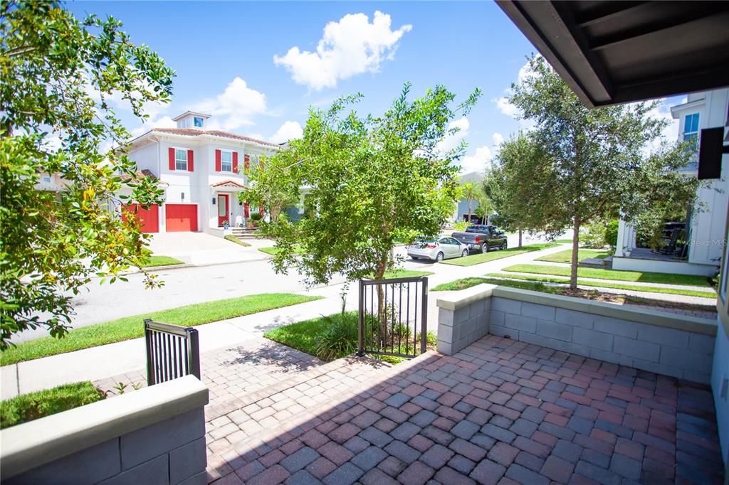 A paved front patio overlooks a residential street with houses and trees under a blue sky — 8202 BELLOW STREET, ORLANDO, FL