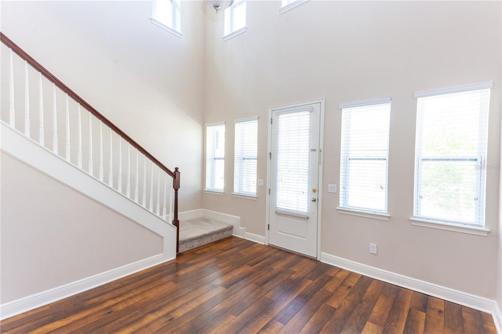 An entryway with wood flooring, a staircase with a white railing, and several tall windows — 8202 BELLOW STREET, ORLANDO, FL