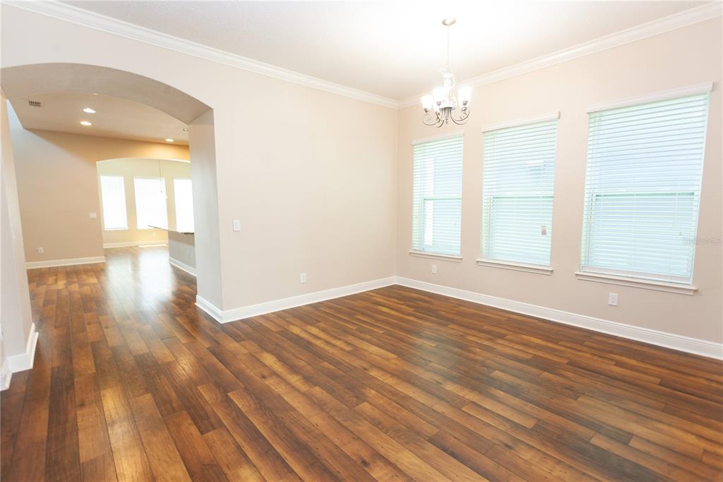 A dining room with wood-look flooring, a chandelier, and three windows with white blinds — 8202 BELLOW STREET, ORLANDO, FL