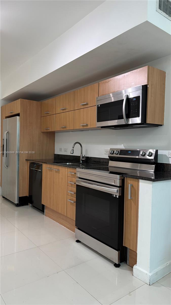 A modern kitchen features light wood cabinets, stainless steel appliances, and dark granite countertops — 350 S Miami Ave # 304, Miami FL 33130, MIAMI, FL
