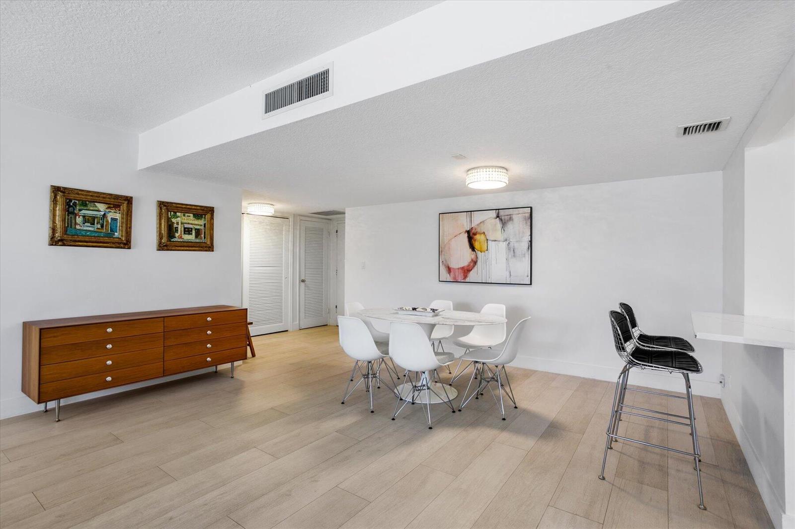 A dining area with a wooden sideboard, a round table with chairs, and bar seating — 2860 S Ocean Boulevard # 216, Palm Beach FL 33480, PALM BEACH, FL