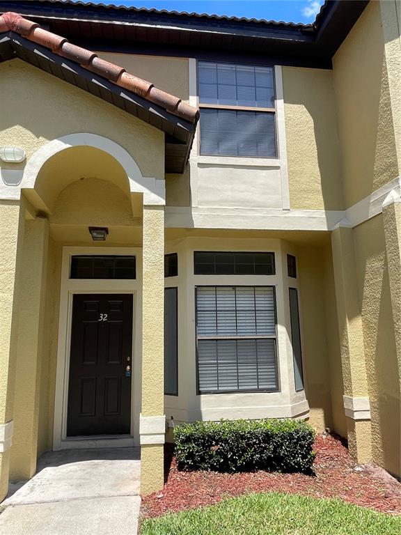 A two-story yellow stucco townhouse exterior features a dark front door and bay window — 6007 SCOTCHWOOD GLEN UNIT 32, ORLANDO, FL