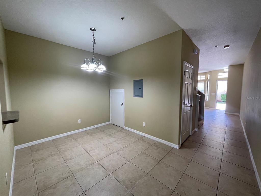A dining area features tile flooring, a chandelier, a small door, and a circuit breaker panel — 6007 SCOTCHWOOD GLEN UNIT 32, ORLANDO, FL