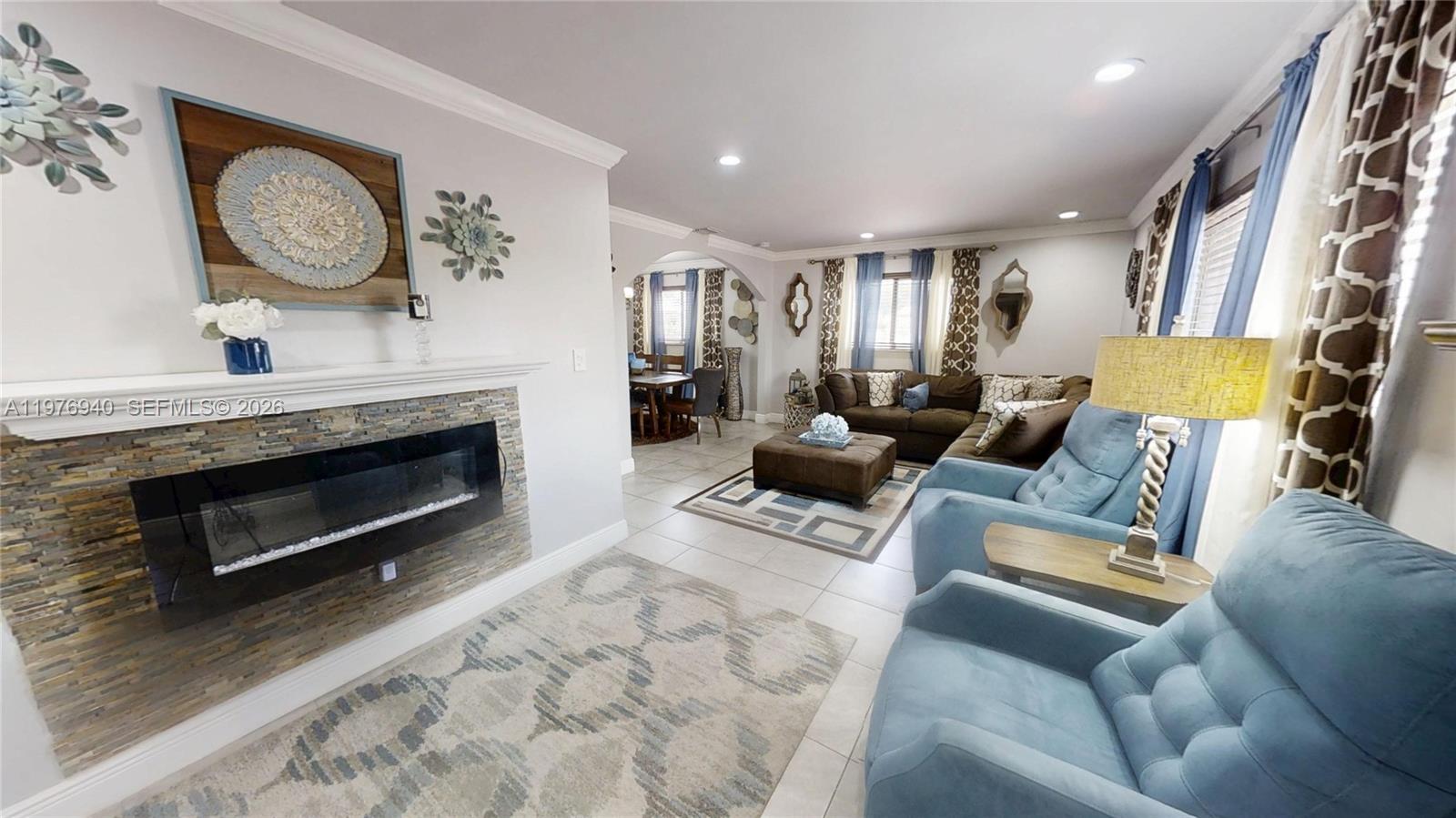 A living room features a stone fireplace, blue armchairs, and a brown sectional sofa — 705 NW 8th Ave, Florida City FL 33034, FLORIDA CITY, FL