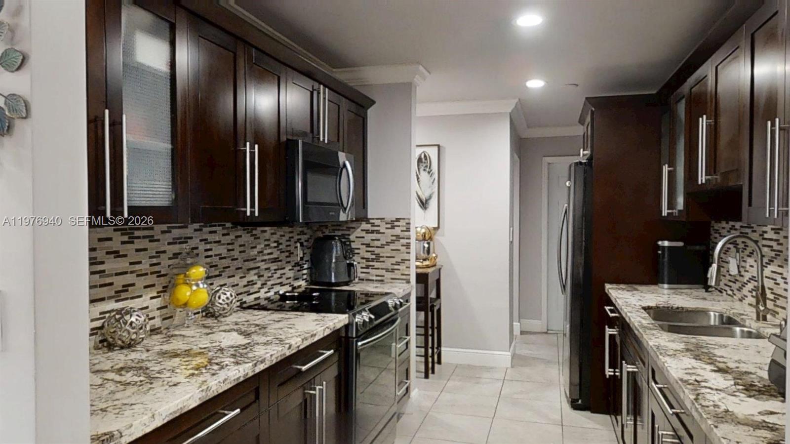 A kitchen features dark wood cabinets, granite countertops, a tiled backsplash, and stainless steel appliances — 705 NW 8th Ave, Florida City FL 33034, FLORIDA CITY, FL