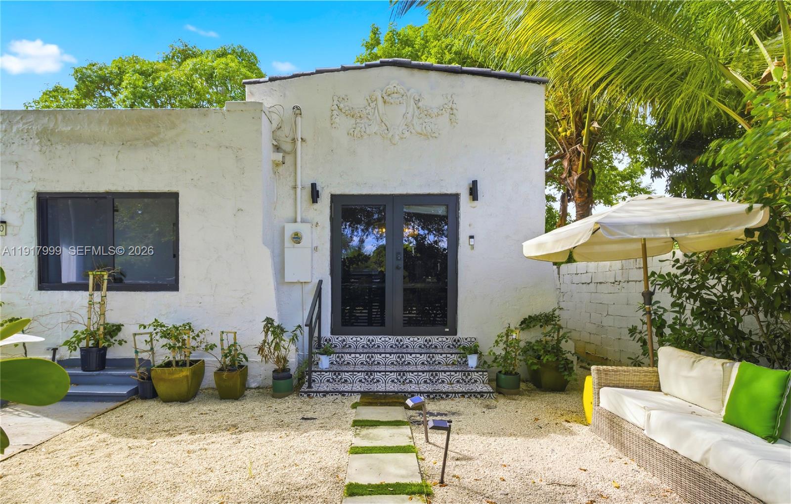 A white stucco building exterior features a patterned tile staircase leading to double glass doors — 8270 NE 1st Pl, Miami FL 33138, MIAMI, FL