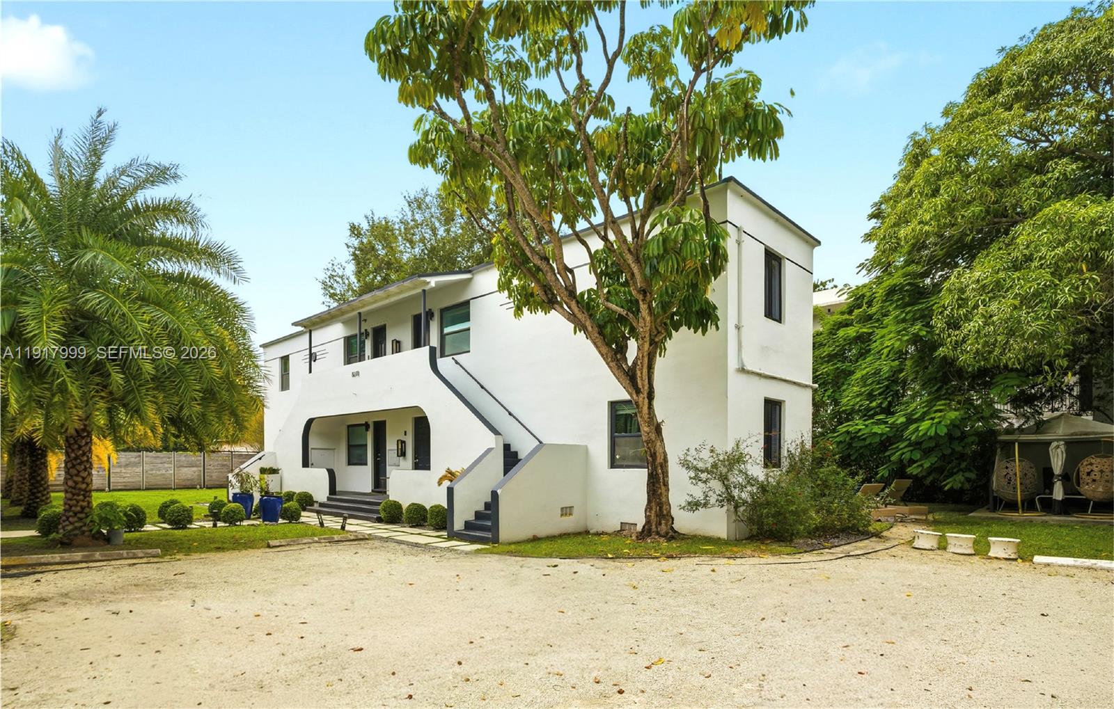 A two-story white building with an exterior staircase stands on a gravel lot — 8270 NE 1st Pl, Miami FL 33138, MIAMI, FL