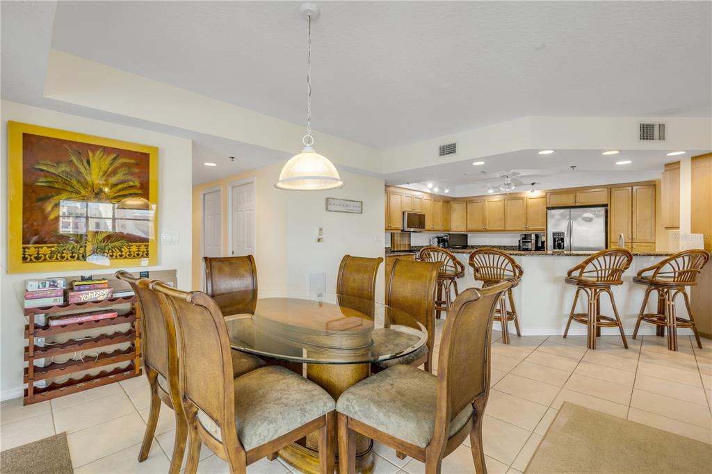 A dining area with a glass table and chairs sits adjacent to an open kitchen — 5300 S ATLANTIC AVENUE UNIT 8-601, NEW SMYRNA BEACH, FL