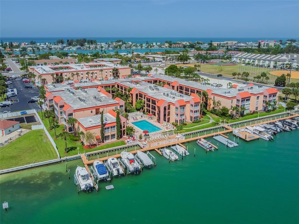 An aerial view of a waterfront apartment complex with a pool and private boat slips — 8931 BLIND PASS ROAD UNIT 257, ST PETE BEACH, FL