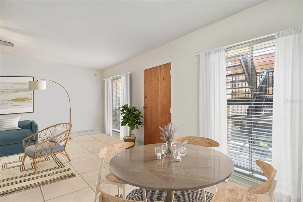 A living and dining area features tile floors, a round table, and a wooden door — 8931 BLIND PASS ROAD UNIT 257, ST PETE BEACH, FL