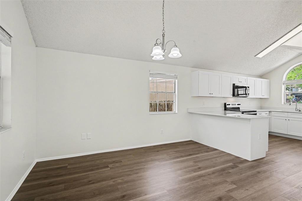 A dining area with wood-look flooring, a chandelier, and an adjacent white kitchen — 311 TIBURON COURT, ORLANDO, FL