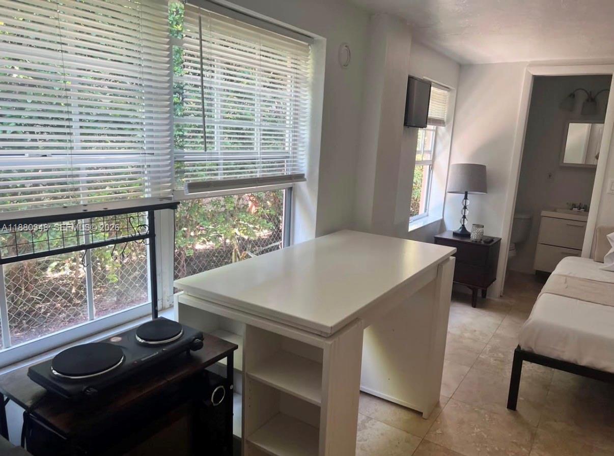 A small room features a white desk, a portable stove, a bed, and an attached bathroom — 1949 NE 173rd St # 0, North Miami Beach FL 33162, NORTH MIAMI BEACH, FL